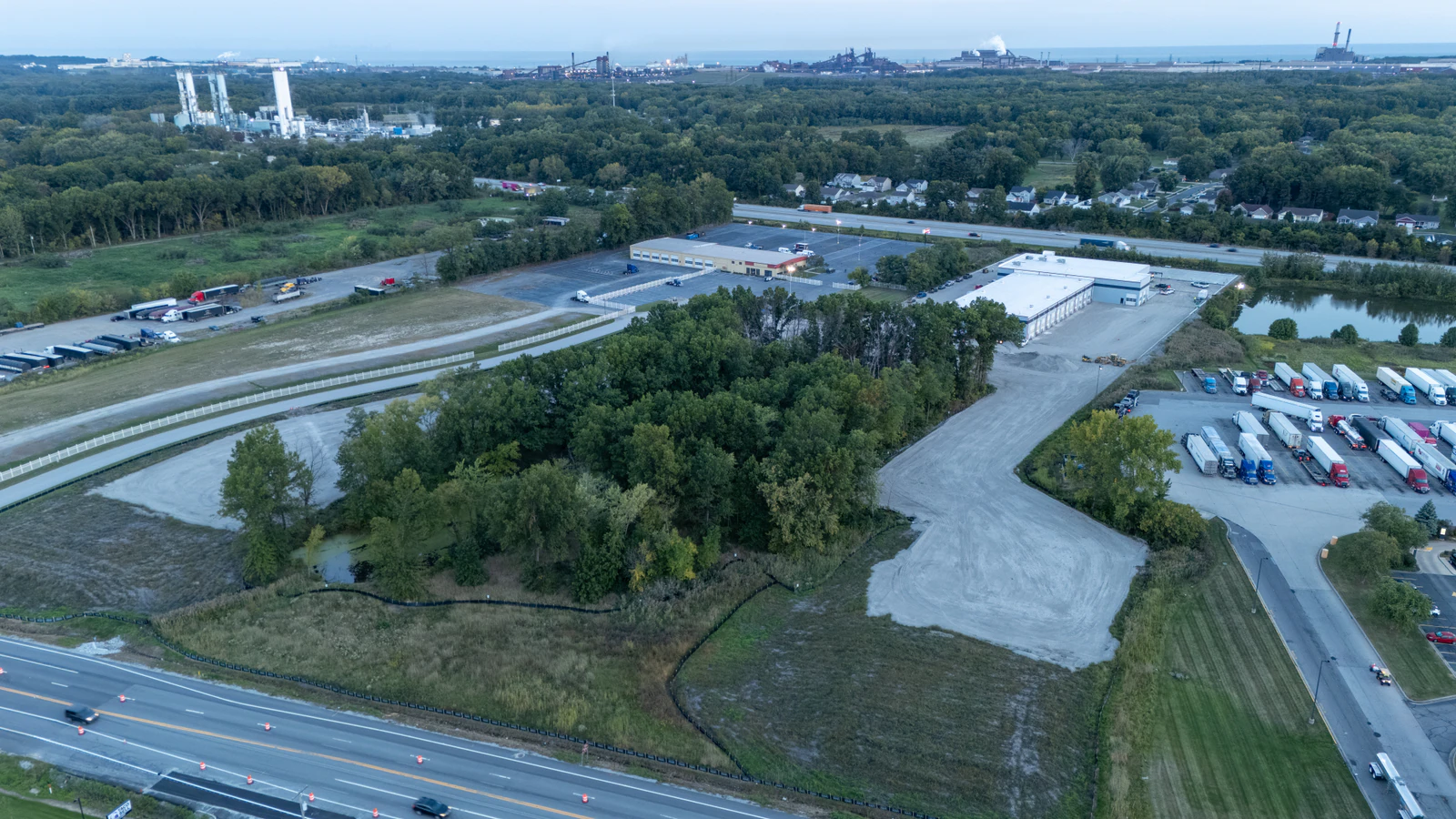 Dusk aerial view of the Rihm Kenworth dealership and its new concrete lot beside the highway interchange
