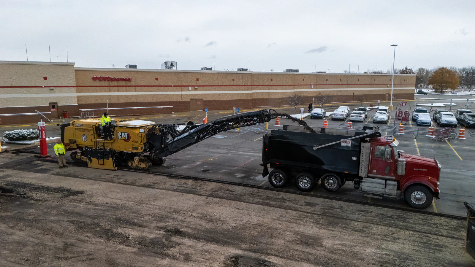 Asphalt milling machine loading a dump truck while removing old pavement from a Target store parking lot